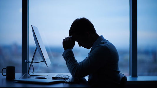 a man with his hands on his head at a desk